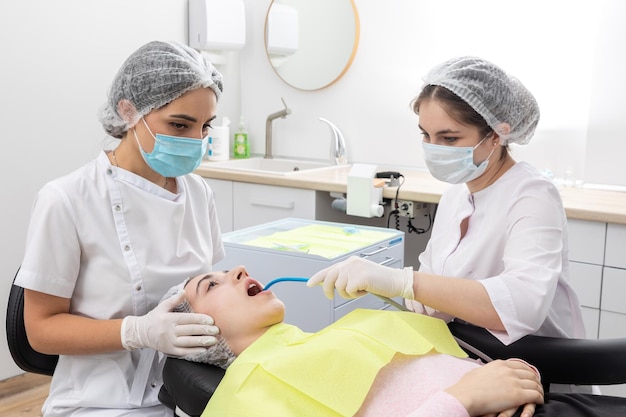 Chirurgo dentista professionista e assistente che esegue operazioni odontoiatriche in una clinica con attrezzature moderne