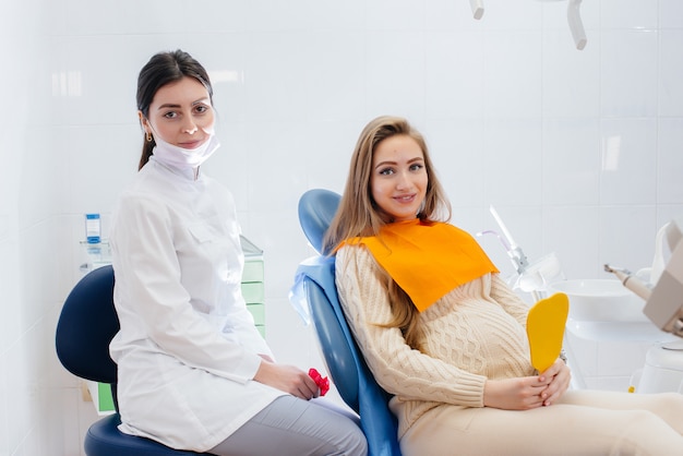 A professional dentist treats and examines the oral cavity of a pregnant woman in a modern dental office