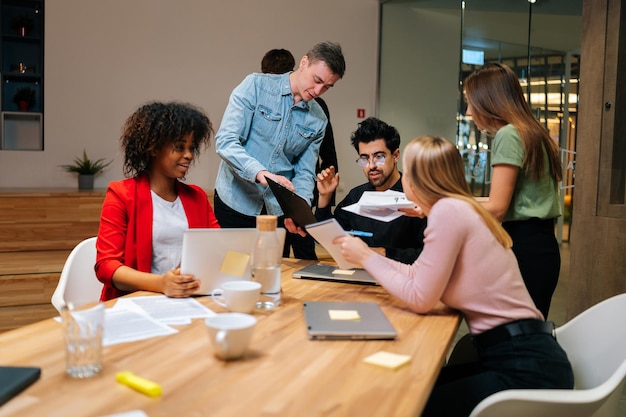 Professional diverse corporate business team female and male workers take part at group brainstorming discussion of financial report paperwork engaged