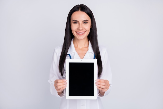 Professional doc lady showing e-book tablet on grey color background