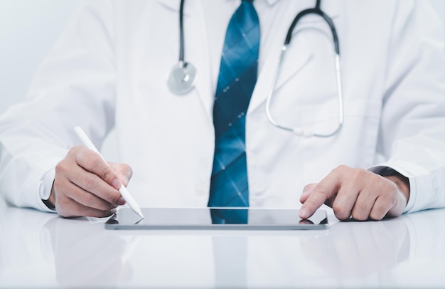 professional doctor man wearing a uniform using a device tablet of hospital doctor touchscreen tablet for health care and treatment remote from internet online patient doctor use technology concept