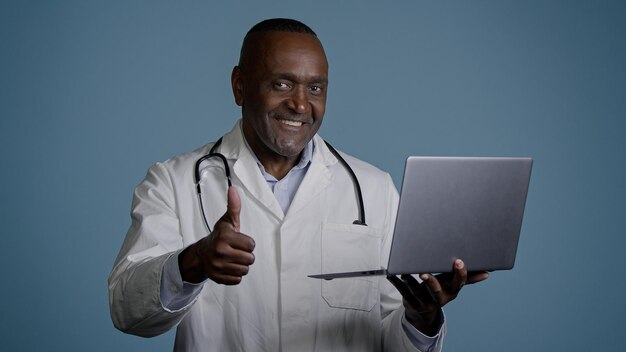 professional doctor in medical gown using laptop consulting patient showing thumb up gesture