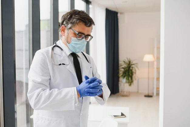 Medico professionista in maschera medica che indossa guanti medico sicuro in camice da laboratorio che indossa protezione durante l'epidemia di covid19 prevenzione delle malattie virali