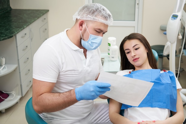 Il medico professionista mostra l'immagine del paziente dei denti nel suo studio dentistico medico.