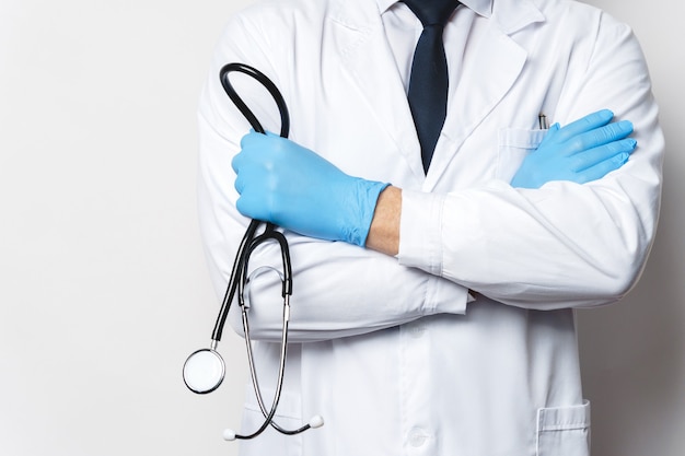 Professional doctor with the stethoscope against gray wall