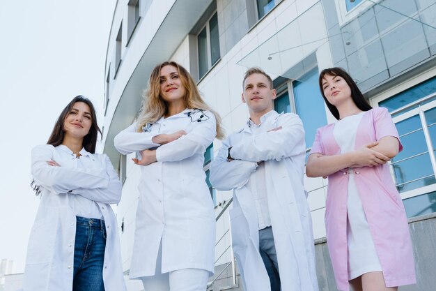 Foto medici professionisti posano fuori dalla clinica una squadra di medici in uniforme quattro persone con le braccia incrociate sul petto