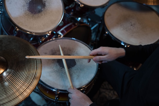 Foto primo piano professionale della batteria. uomo batterista con bacchette che suona batteria e piatti, al concerto rock di musica dal vivo o in studio di registrazione