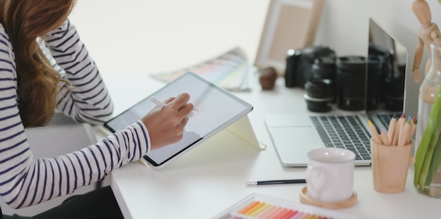 Professional editing her project with tablet in modern workplace 