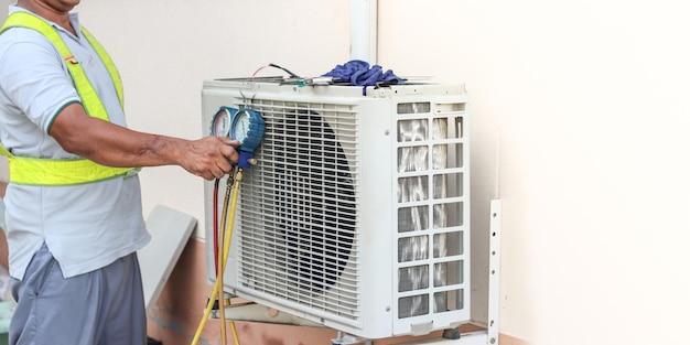 A professional electrician man is fixing a heavy air conditioner Model is actual repairman electrician Air Conditioning Repair