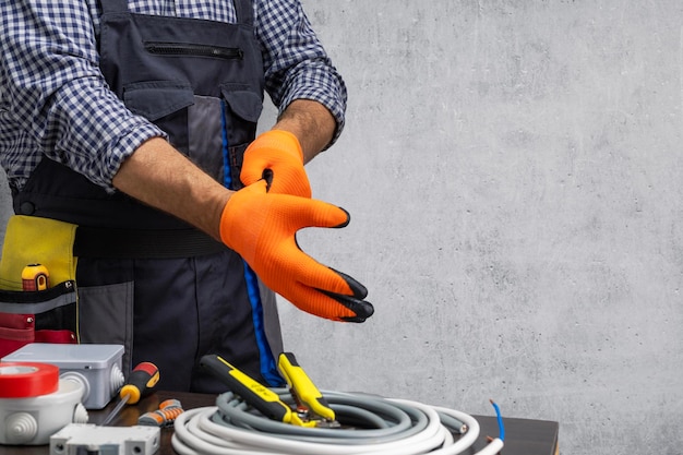 professional electrician technician in uniform putting protective gloves