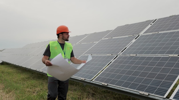 Ingegnere professionista che impara la progettazione del piano cartaceo dell'impianto solare cammina sulla costruzione ecologica dell'impianto solare. energia sostenibile. concetto di energia verde.