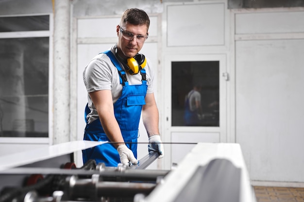 professional engineer man in blue uniform works in factory rolled metal metal processing and manufacturing of metal fence