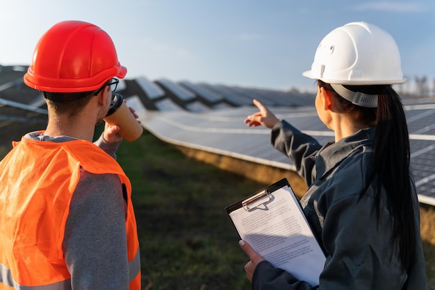 Professional engineers in helmet and uniform looking to the construction of solar power plant