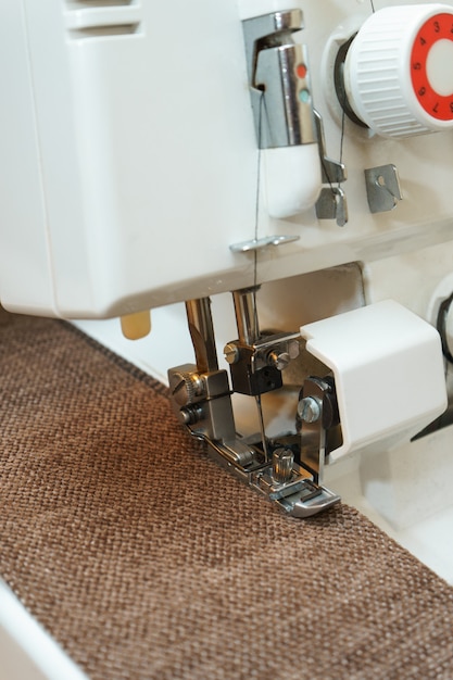 Professional equipment. Modern overlock sewing machine pressure foot in use with item of clothing. Close up photo.