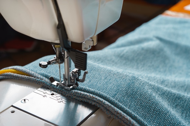 Professional equipment. Modern sewing machine with special pressure foot. The process of sewing a decorative edging cord of blue item of clothing.