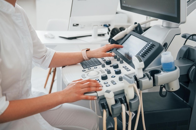 Professional female clinic worker in white coat is indoors in the cabinet