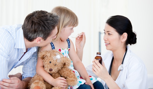 Professional female doctor giving syrup to a little girl 