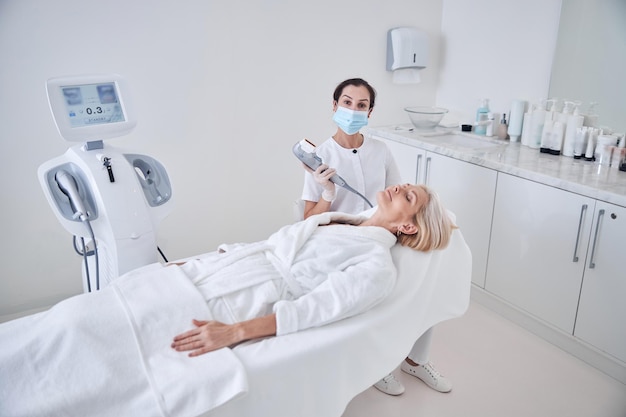 professional female doctor working with patient while applying special ultrasound machine