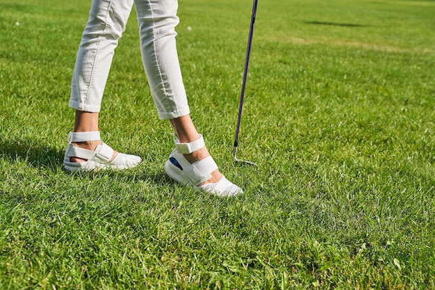 a professional female golfer with a golf club standing on the grass