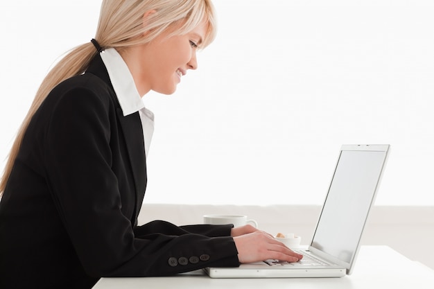 Professional female having her breakfast while relaxing with a laptop