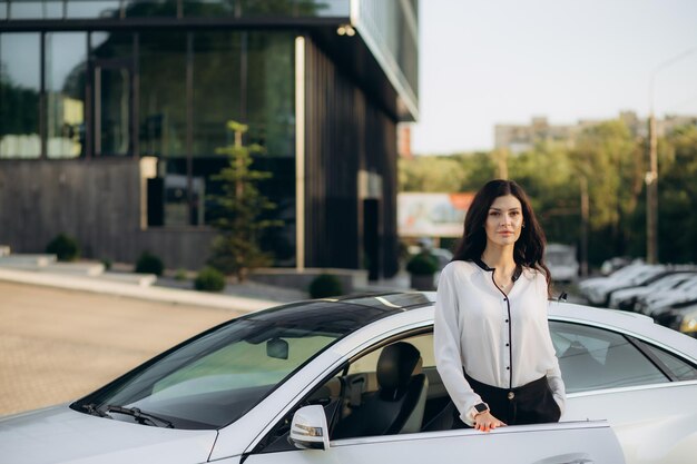 Профессиональная женщина-менеджер с планшетом стоит возле машины в офисном здании