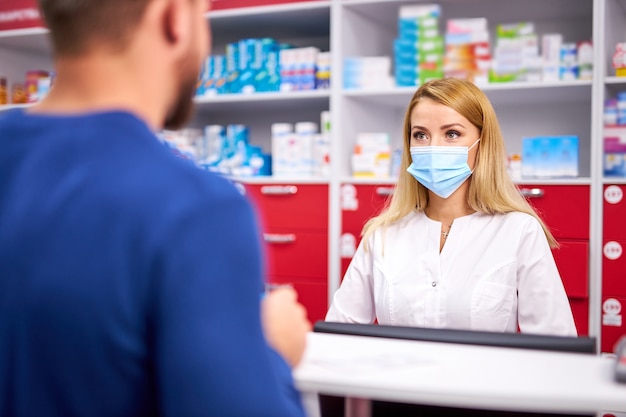 Professional female pharmacist helping male customer choosing prescription drugs