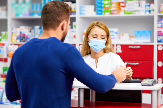 Professional female pharmacist helping male customer