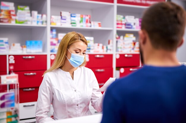 Professional female pharmacist helping male customer