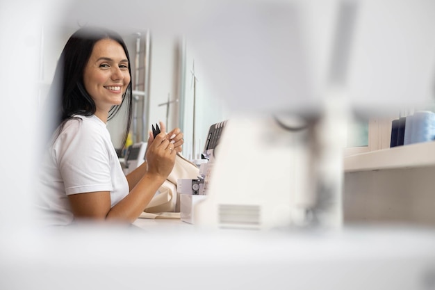 Professional female seamstress thread a needle use electric sewing machine at sew workshop