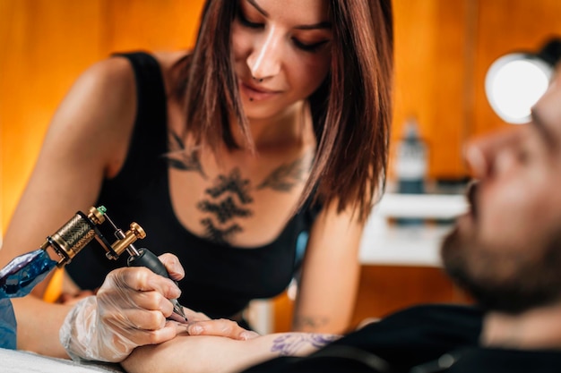 Photo professional female tattooist working in a tattoo studio