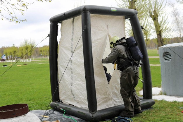 A professional firefighter in a black special fireproof suit prepares to assemble a white oxygen