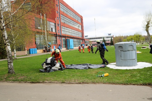 Professional firefighters rescuers in protective fireproof suits helmets and gas masks flee people