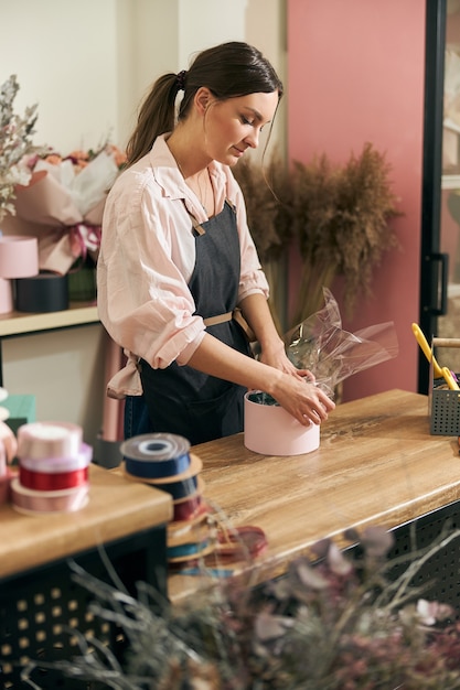 プロの花屋の若い女性がフラワーショップで花束をやっています