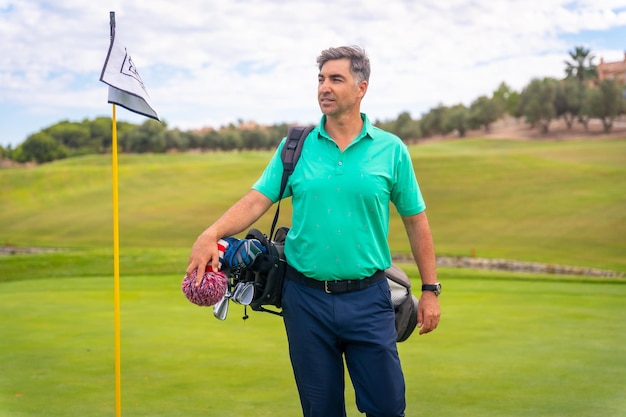 Профессиональный игрок в гольф на поле для гольфа рядом с флагом на зеленом
