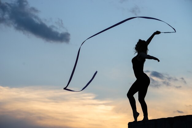 Профессиональный танцор женщины гимнастки с лентой на небе.