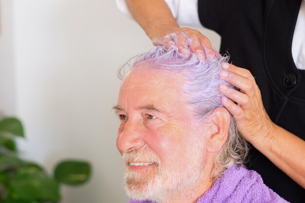 Il parrucchiere professionista applica uno speciale colore viola per rimuovere il colore giallo dai capelli bianchi