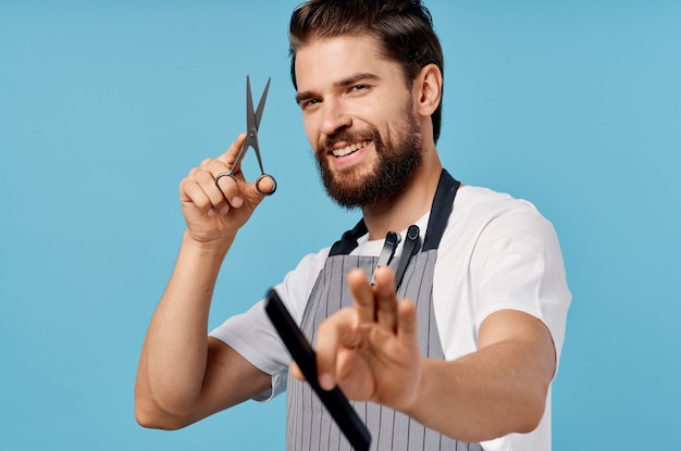 Photo professional hairdresser in gray aprons fashionable hairstyle bushy beard scissors comb man.