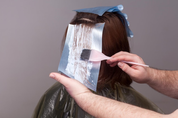 Foto parrucchiere professionista che tiene la spazzola e tinge i capelli del suo cliente