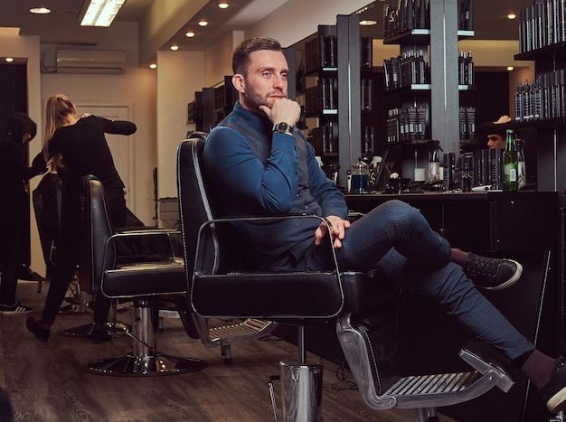 Photo a professional hairdresser sitting on a barber chair, waiting for the next customer.