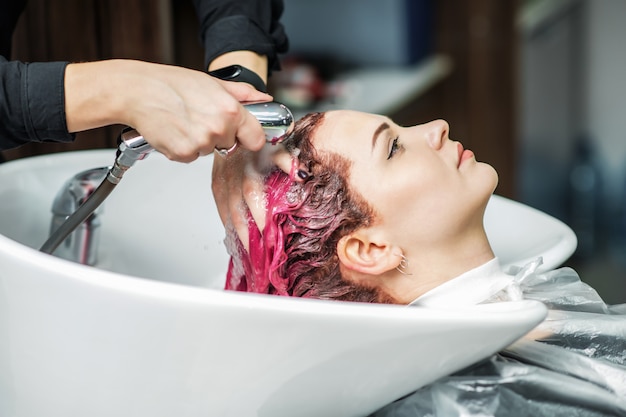 Professional hairdresser washing hair of a beautiful client