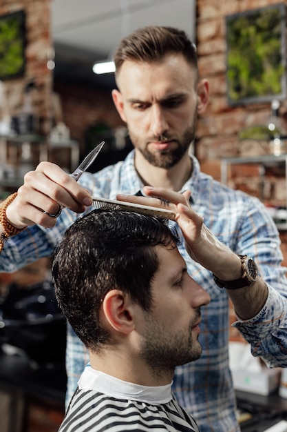 Professional hairdresser working with client in barbershop