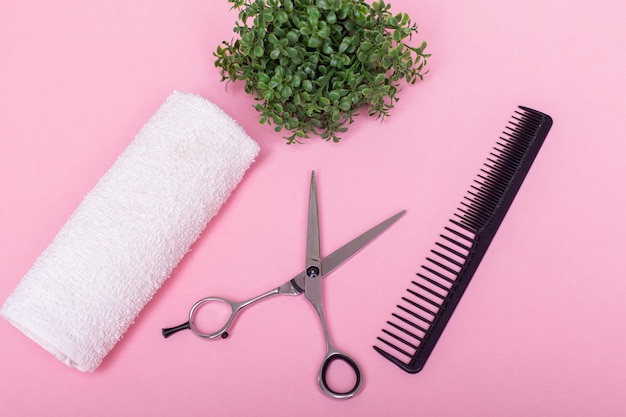 Professional hairdressers scissors and brush on pink background