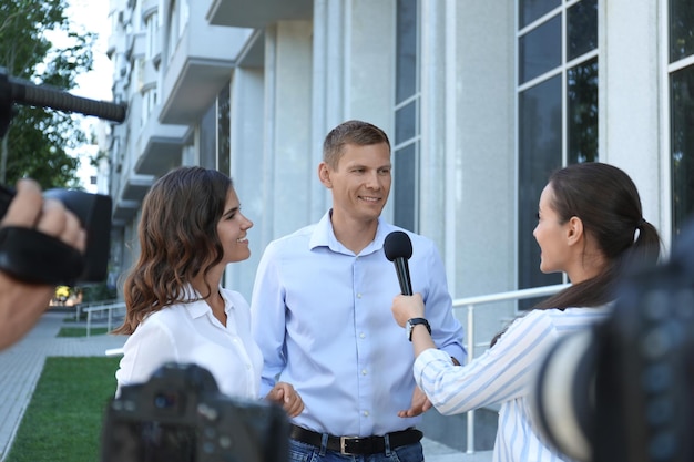 Professional journalist and operator with video camera taking interview outdoors