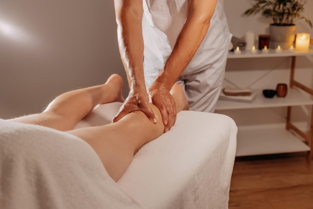 Massaggio professionale alle gambe nel salone spa sullo sfondo delle candele