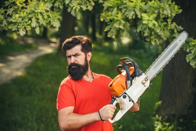 Photo professional lumberjack holding chainsaw in the forest lumberjack holding the chainsaw agriculture a...