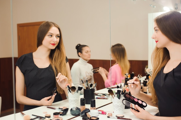 A professional make-up artist prepares to work in front of a mirror.