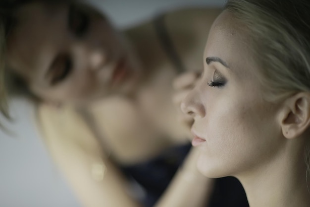 Foto trucco professionale nel salone di bellezza / master fa un trucco estivo professionale fresco di una bellissima modella nel salone