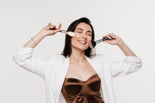 Professional makeup artist with makeup brushes on white background Attractive girl is holding eye shadow brushes and smiling