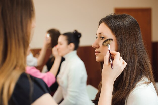 Professional makeup artist working with beautiful young woman.