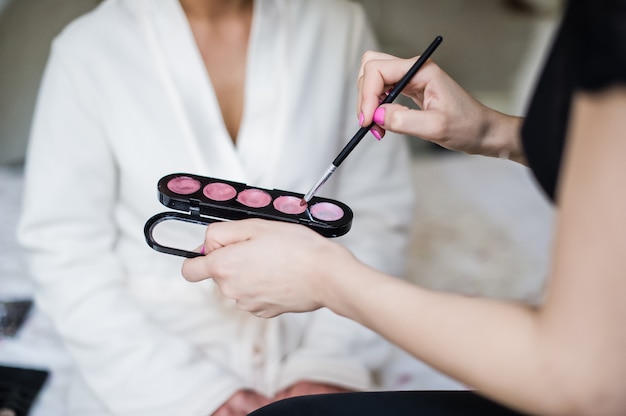 Professional makeup artist working with young bride